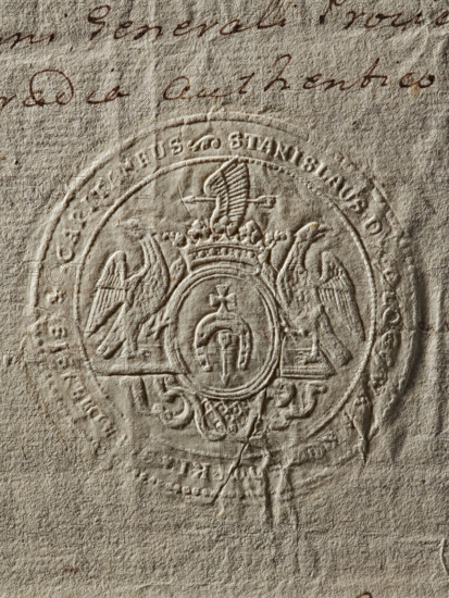 Seal of Stanislaw Kossowski, Starost of Sieradz. Round seal impression. Oval shield with the Dolega coat of arms and a jewel above a rank crown, supported by two eagles standing on a decorative console. Inscription in the rim: 'STANISLAUS DE GLOGOWA KOSSOWSKI SIRADIENSIS CAPITANEUS.' Dated 1772, Poland., A close-up of textured beige paper showing an embossed circular seal with ornate heraldic imagery; the seal displays a central oval surrounded by decorative elements including a crown, a pair of stylized birds with outstretched wings, and flowing ornamental scrollwork, all pressed into the paper creating raised and recessed areas; the paper surface shows wrinkles, creases, and rough fibers with a few small darker spots and subtle shadows emphasizing the embossing; faint cursive handwriting in brown ink is visible near the top edge.