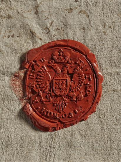 Seal of the Main Provision Commission; oval wax impression of the seal of the Main Provision Commission. In the field, a double-headed Tsarist eagle with a shield bearing the Pursuit on its chest. In the rim, a partially illegible inscription in Russian. 1775, Poland; stamp; dimensions 31.5 mm and 34.5 mm. Maker: Zurakowski, Witold (?-1927)., A close-up of a circular red wax seal pressed onto a textured beige surface, the seal showing cracks and chips with an embossed double-headed bird and a small central shield shape, surrounded by decorative raised edges and radial patterns; the surrounding paper shows subtle stains and fibers in shades of beige and light brown, and there is a faint smudge of red wax beside the seal.