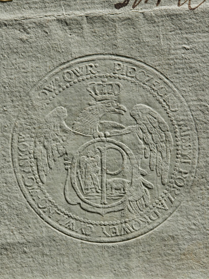 Round dry impression of the seal of the Civil-Military Order Commission of Owruck County (1792). Round seal: crowned eagle with head facing left in the field; a decorative shield showing St. Michael holding a downward-pointing sword in one hand and a sword scabbard in the other, with a central capital letter P and a bear (coats of arms of the Kilów Voivodeship). Rim inscription: 'PIECZEC KOMMISSYI PORZADKOWEY CIWILNO-WOYSKOWEY POW : OWR.' Poland, Owrucki poviat., An embossed circular seal pressed into textured paper showing a detailed eagle with outstretched wings and a crown above its head, a central oval medallion over the eagle's chest containing a standing human figure and an animal, and a ring of bead-like dots forming an inner border; the paper is a muted greenish-gray with subtle darker and lighter variations and visible fibrous texture.