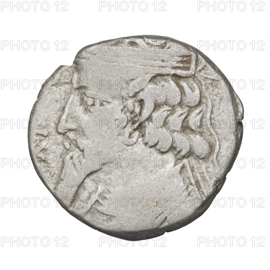 Tetradrachm of Artabanos II (king of Parthia; 10–40 AD). Obverse: bust of Artabanos II facing left, wearing a diadem and armor. Reverse: Artabanos seated on a throne facing left, receiving a palm from a standing female figure (possibly Nike); at his feet a kneeling male figure holds out a wreath. Iconography: wreaths, palms, Nike standing. Parthian Kingdom, Iran. Coin. Diameter 24.0 × 26.0 mm; weight 13.55 g.