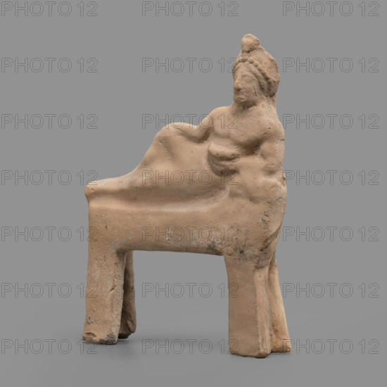 Figurine of a feasting Dionysus: figurine of a feasting man resting on a bed in a semi-reclining position, leaning on his left elbow and holding a cup in that hand. The torso is naked and the lower part covered from the waist with a cloak, the end of which is thrown over the left forearm onto a pillow. On the head is a diadem decorated with pearls, an astral rosette above which a lotus flower protrudes. Red clay, medium-grained with tiny mica particles. 5th century BC (dating before a 2019 revision: late 6th century BC; analogous artifact dated to 480–470 BC). Tarentum. Figurine; height 19 cm, width 15.2 cm, depth 3.3 cm, weight 0.34 kg.