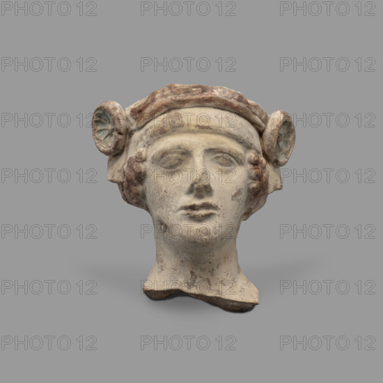 Head of a figurine of Dionysus. Head of a young man with a face devoid of [expression?], wide compact mouth, triangularly outlined face with carved cheeks, large eyes, a prominent nose and gently outlined eyebrows. The youth wears a diadem decorated with rosettes on the sides and a thick wreath. Traces of red paint (cinnabar) on the hair, lips and diadem; blue in the rosettes (in the recesses) and on the vertebrae. 5th–4th century BC, Taranto, Southern Italy (Italy). Terracotta figurine, height 8.7 cm, width 8.3 cm, depth 6.3 cm, weight 0.28 kg.