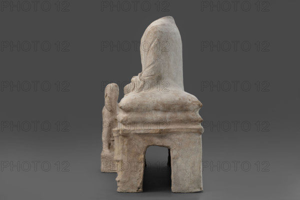 Depiction of a deceased person on a keline and a servant, Scen.Gal.Klass., Cyprus - partage. The sculpture depicts a man banqueting in a semi-reclining position on a keline (bed). His upright torso is supported by his left elbow placed on two pillows. The man is dressed in a long, finely pleated chiton and himation. In front of the bed, at the side of the banqueter's legs, stands a small boy dressed in a chiton on a cuboid base. 4th century BC (dating before the 2019 revision: 450–375 BC; Cypriot-Classical Period). Marion. Sculpture. Height 45 cm, width 53 cm, depth 24 cm, weight 13.03 kg.