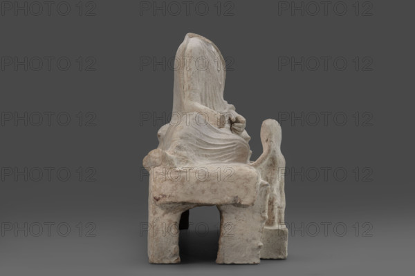 Depiction of a deceased person on a keline and a servant, author, Scen.Gal.Klass., Cyprus - partage. The sculpture depicts a man banqueting in a semi-reclining position on a keline (bed). His upright torso is supported by his left elbow placed on two pillows. The man is dressed in a long, finely pleated chiton and himation. In front of the bed, at the side of the banqueter's legs, stands a small boy dressed in a chiton on a cuboid base. 4th century BC (dating before the 2019 revision: 450–375 BC; Cypriot-Classical Period). Marion. Sculpture; height 45 cm, width 53 cm, depth 24 cm, weight 13.03 kg.
