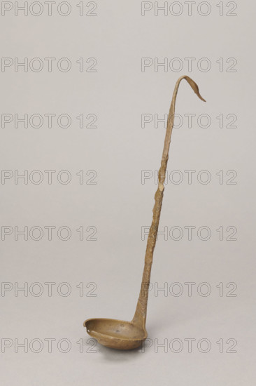 Shallow dipper with a quadrilateral handle, narrowed at the top. The end of the handle is in the shape of an elongated bird's head (swan). The round dipper has a shallow bottom, its edges are slightly thickened. A hole is visible in the dipper. The surface of the object is uneven (corroded). Etruria, vessel, height 31.2 cm, width 7.5 cm.