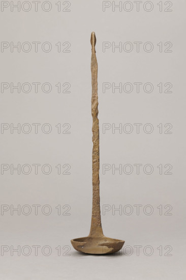 Shallow dipper with a quadrilateral handle narrowed at the top. The end of the handle is in the shape of an elongated bird's head (swan). The round dipper has a shallow bottom, its edges are slightly thickened. A hole is visible in the dipper. The surface of the object is uneven (corroded). Etruria; vessel; height 31.2 cm, width 7.5 cm; maker/date: Antoni Madeyski (1862–1939)