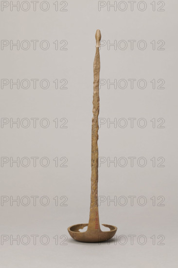 Shallow dipper with a quadrilateral handle, narrowed at the top. The end of the handle is in the shape of an elongated bird's head (swan). The round dipper has a shallow bottom, its edges are slightly thickened. A hole is visible in the dipper. The surface of the object is uneven (corroded). Etruria, vessel, height 31.2 cm, width 7.5 cm.