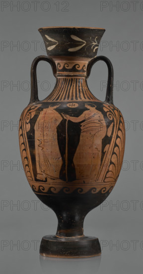 Red-figure amphora, Apulian workshop, Classical Period. Wide, tapering foot supporting a cylindrical stem merging into a belly with short horizontal handles arching into a narrow neck topped by a tall, diagonally widening spout covered with floral ornamentation. Neck decorated at top with a wavy ornament; lower section ingot-shaped. Two ribbon-like handles run from the shoulders to the lower edge of the rim. Both sides of the body bear painted figurative scenes. Side A: a naked man and a dressed woman standing opposite each other with an altar between them; the man holds a bowl in his outstretched left hand with a cloak slung over it, his right arm down and weight on his left leg; the woman wears a long chiton fastened at the shoulders and tied at the waist. Side B: two young men facing each other, wearing cloaks; the young man on the right leans on a long stick with his right arm outstretched. Beneath the handles are large palmettes surrounded by a plant motif; the lower part of the b...
