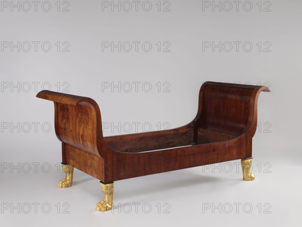 Bed with animal-paw legs, Empire style, mahogany, c. 1815–1830. S-shaped outward-curving pediments of equal height and straight side boards; supported by four carved, gilded legs in the form of furry animal paws. Pediment frames with single panels, strong upturns at the top and simple bottoms, connected to the sides with screws and hooks. Upper corners of the sides arch into the pediment frames; inner bottom edges have glued-on toothed strips supporting the cross slats under the mattress. One pediment veneered on the outside with ash-stained mahogany. Bedrooms; Warsaw, Central Europe. Height 103 cm; width 192 cm; depth 94.5 cm.
