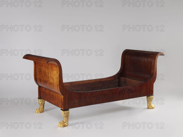 Bed with S-shaped outward-curving pediments of equal height and straight side boards, supported by four carved, gilded legs in the form of furry animal paws. Mahogany, with frame pediments having single panels, strong upturns at the top and simple bottoms, connected to the sides with screws and hooks. Upper corners of the sides arch into the pediment frames; inner bottom has glued-on toothed strips supporting the cross slats under the mattress. One pediment veneered on the outside with ash stained mahogany. Empire style, 1815–1830, Warsaw, Central Europe. Dimensions: height 103 cm, width 192 cm, depth 94.5 cm.