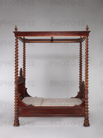 Four-poster double bed with flat pediments topped with a wavy pattern, framed by tall spiral columns serving as legs and supporting the profiled cornice of the canopy creating a rectangular frame. Higher headboard. The edges of the applied pediment finials are bordered with a fleshy half-cylinder forming channel and S-shaped sections, as well as elongated cartouches with a rounded, convex field similar to a cabochon. Boarded sides at the pediments are widened in an arched manner with a channel-decorated edge; decorated on the outside with a glued-on profiled strip creating the outline of an elongated oval. Spiral pinnacles at the corners of the canopy. The sides are connected to the pediments with tongue-and-groove joints and pairs of steel screws placed on the inside. The legs are spherical, with a hollow bottom to accommodate a steel roller. Two-piece mattress, with a high back, on springs, is supported by crosswise boards placed on slats attached to the bottom of the sides, on their...
