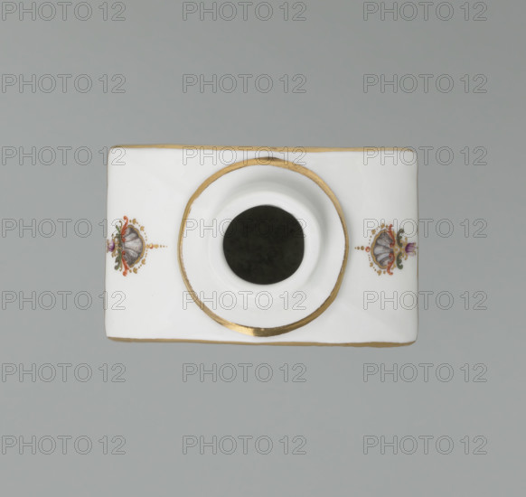 Four-sided tea bowl, Meissen (circa 1750), manufacturer active 1710–1763. Tea bowl with a rectangular base, semicircular arched sides at the top, a circular opening and a short hoop neck (lid missing). On the larger walls, cartouche frames with two purple draperies suspended at the sides on small flower bouquets and dry rocaille, topped and bottomed on the axis of symmetry by brick-red draperies suspended on plant branches. The cartouches contain purple camaieu landscape miniatures with architecture and staffage: (1) a multi-span bridge with a cross and a figure on the left; (2) on a rocky outcrop, a structure resembling a three-stepped tower. On the smaller walls and on both sides of the neck’s vault are colorful ornamental emblems with plant motifs and palmettes. The edges of the vault and the step around the neck are trimmed in gold. Height 10.5 cm, width 7 cm, depth 4.6 cm.