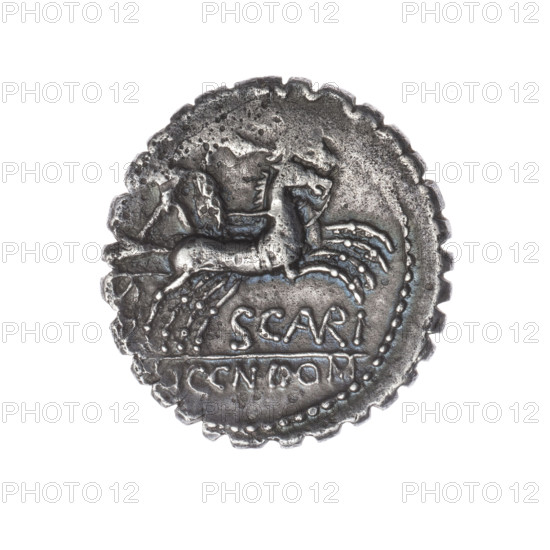 Denarius serratus, M. Aurelius Scaurus (publisher), L. Licinius Crassus (publisher), Cn. Domitius Ahenobarbus (publisher); 118 BC, Roman Republic. Obverse: Head of Roma in an Attic helmet right; in front inscription M.AVRELI (VR in ligature); behind ROMA and value sign X (crossed out). Pearl border. Reverse: Naked warrior on a biga right, holding reins, shield and carnyx in left hand and a spear in right; below inscription SCAVRI (AVR in ligature); under the line inscription LIC.CN.DOM. Pearl border. Coin from Narbonne; denarius serratus; diameter 19.1 mm; weight 3.83 g; axis 135°.