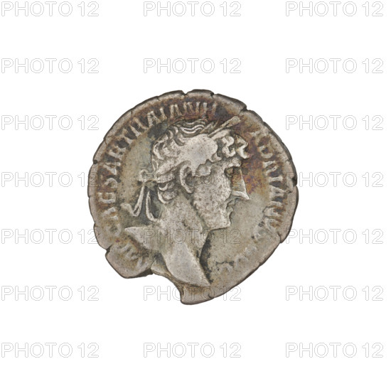 Denarius of Hadrian (76–138; Roman emperor 117–138). Obverse: Bust of Hadrian with laurel wreath facing right; rim inscription IMPCAESARTRAIANHADRIANVSAVG. Reverse: Roma seated left on a chair, wearing a long robe and helmet; in her outstretched right hand she holds a figure of Victoria, in her left hand a vertical spear, with a shield behind her; rim inscription PM TR P COS III. Date: 119–122. Rome, Roman Empire (27 BC–476). Coin; weight 2.68 g.