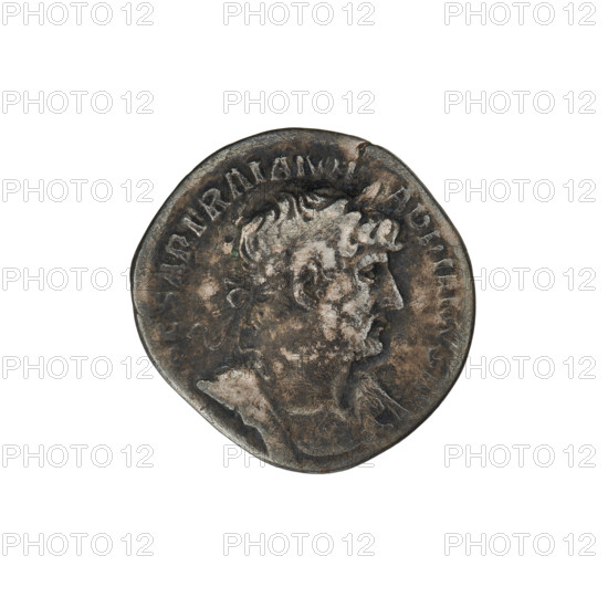 Denarius of Hadrian (76–138; Roman emperor 117–138). Obverse: Bust of Hadrian with laurel wreath facing right; rim inscription IMPCAESARTRAIANHADRIANVSAVG. Reverse: Roma seated left on a chair, wearing a long robe and helmet, holding a figure of Victoria in her outstretched right hand, a vertical spear in her left hand, with a shield behind her; rim inscription PM TR P COS III. Date: 119–122. Rome, Roman Empire (27 BC–476). Coin, weight 3.22 g.