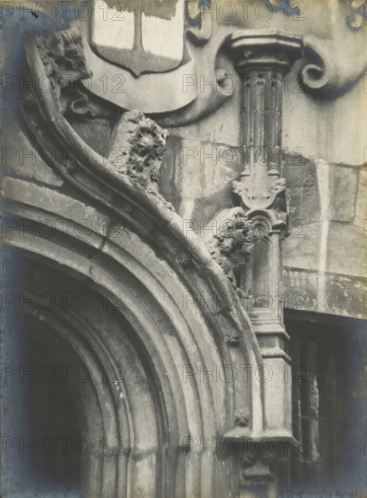 Detail of the entrance gate of the Gemeenlandshuis on the Oude Delft in Delft, Gemeentelandshuis. Oude Delft WZ No. 167. Entrance detail, photograph, inscription: 'The right of reproduction of these photos is reserved by the Publisher.', number: '13', inscription: 'Delft. Early 16th century and mid-17th century.', Delft, c. 1900 - c. 1904, photographer, paper, pasteboard, gelatin silver print, height 157 mm x width 116 mm, gate, entrance, Gemeenlandshuis, A close-up black-and-white photograph of an ornate stone doorway showing layered rounded arches with weathered surfaces, carved decorative elements including floral and scroll motifs, a fluted column with a capital, and sculpted reliefs on the arch supports, all set against a stone wall with visible texture and areas of staining.