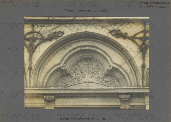 Facade Koornmarkt WZ No. 81. Tympan ground floor, Decoration on the facade of a house on the Koornmarkt in Delft, depicting a niche with leaf motifs, photograph, inscription: 'The right of reproduction of these photos is reserved by the Publisher.', number: '29', inscription: 'Delft. Early Renaissance. 1st half of the 16th century.', Delft, c. 1900 - c. 1904, photographer, paper, pasteboard, gelatin silver print, gelatin silver development, height 117 mm x width 158 mm, ornament derived from plant forms, urban housing, ornament derived from architectural details, Koornmarkt, A close-up view of an arched stone architectural element set within a rectangular frame, showing curved moldings and layered semicircular arches with ornamental carved foliage and scrollwork in the central archway, flanked by vertical pilaster-like structures with carved capitals and horizontal ledges, all rendered in grayscale tones with visible surface texture and faint cracks.