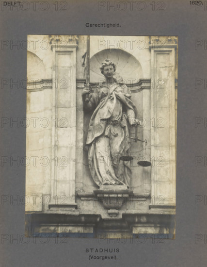 Sculpture of Lady Justice on the town hall in Delft, Town Hall (Facade). Justice, photograph, inscription: 'The right of reproduction of these photos is reserved by the Publisher.', inscription: 'Delft. 1620.', number: '49', Delft, c. 1900 - c. 1904, photographer, paper, pasteboard, gelatin silver print, height 156 mm x width 116 mm, town hall, 'Giudice' (Ripa), A grayscale photograph of a sculpted female figure set into an architectural niche of a stone facade, the figure draped in flowing garments with one hand raised holding a vertical object and the other hand extended slightly downward holding a set of suspended pans, the niche framed by rectangular pilasters and decorative molding, the statue standing on a carved pedestal above a projecting cornice, with parts of the weathered stone surface showing discoloration and surface texture.