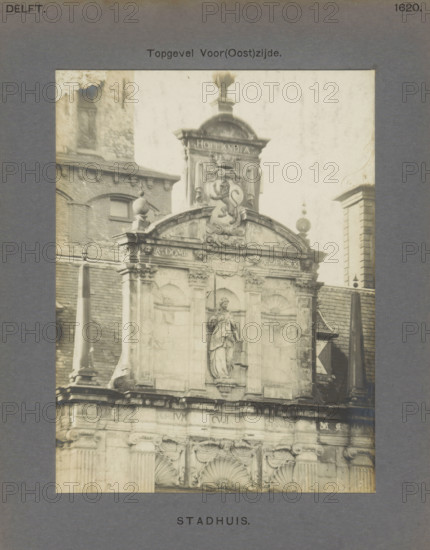 Town Hall. Gable Front (East) Side, Gable of the town hall in Delft with a sculpture of Lady Justice and a coat of arms with a lion, photograph, inscription: 'Delft. 1620.', number: '51', inscription: 'The right of reproduction of these photos is reserved by the Publisher.', Delft, c. 1900 - c. 1904, photographer, paper, pasteboard, gelatin silver print, height 157 mm x width 118 mm, town hall, coat of arms (as symbol of the state, etc.), balustrade, 'Giudice' (Ripa), A sepia-toned photograph of an ornate stone building facade framed by a grey mat, showing carved architectural details, rounded arches, decorative scrollwork, and sculpted stone figures. The upper portion features a central decorative crest with a sculpted animal relief topped by a rounded ornament and flanked by finials. Below the crest is a recessed niche containing a standing statue draped in flowing garments, holding scales. The facade shows pilasters, carved capitals, and shell-shaped motifs above arched panels, with...