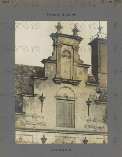 Town Hall. Gable South side, Stepped gable of the town hall in Delft, photograph, number: '52', inscription: 'The right of reproduction of these photos is reserved by the Publisher.', inscription: 'Delft. 1620 and 1760.', Delft, c. 1900 - c. 1904, photographer, paper, pasteboard, gelatin silver print, height 157 mm x width 118 mm, town hall, decorated gable, Stadhuis (Delft), A sepia-toned photograph shows the upper portion of a stone building facade with ornate architectural details. The central section features a pedimented gable with carved scrolls and a recessed arched niche topped by a shell motif, flanked by vertical pilasters and cornices. A double wooden door with simple recessed panels sits below a semicircular arch. Decorative iron fleur-de-lis wall mounts project from the masonry on either side of the facade. Stone plaques with ornate surrounds are set into the wall at mid height. A slate-tiled roof slopes down to the left, and to the right a taller stone chimney or tower ri...