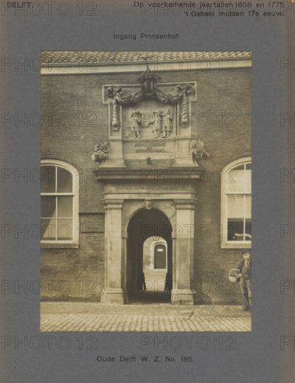 Oude Delft WZ No. 185. Entrance Prinsenhof, Gate of the Prinsenhof in Delft, photograph, inscription: 'Delft. At the dates 1658 and 1775. The whole mid-17th century, ', inscription: 'The right of reproduction of these photos is reserved by the Publisher.', number: '58', Delft, c. 1900 - c. 1904, photographer, paper, pasteboard, gelatin silver print, developed gelatin silver print, height 155 mm x width 116 mm, gate, entrance, Prinsenhof (Delft), A sepia-toned photograph of a brick building façade with a central arched entrance framed by stone columns and an ornate stone relief above the doorway showing sculpted figures and decorative garlands, flanked by two tall windows with divided panes and curtains, cobblestone pavement in front, a narrow passage visible through the arch leading to another arched doorway, a partially visible person standing to the right carrying a basket, and a small bird on the pavement near the entrance.