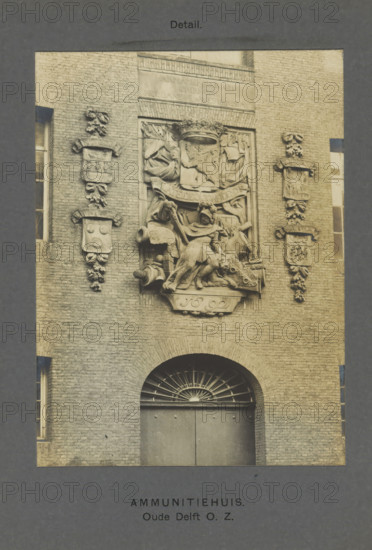 Ammunition House. Old Delft OZ Detail, Relief on the facade of the Armamentarium in Delft, depicting a soldier, lion and a coat of arms with a lion, photograph, inscription: 'Delft. 1692.', inscription: 'The right of reproduction of these photos is reserved by the Publisher.', number: '61', Delft, c. 1900 - c. 1904, photographer, paper, pasteboard, gelatin silver print, developed gelatin silver print, height 155 mm x width 115 mm, coat of arms (as symbol of the state, etc.), decorating 'en relief', appliquéing, A stone facade with an arched doorway topped by a semicircular metal grille sits beneath a rectangular sculptural relief panel featuring a seated armored figure surrounded by draped fabric, shields, a crown, and various carved ornamental elements, flanked vertically by pairs of carved heraldic shields and decorative foliage mounted on the brick wall, with narrow vertical windows visible at the left and right edges.