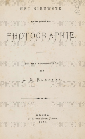 The latest in the field of photography, book, writer (clerical worker): LG Kleffel, Berlin, publisher: GB van Goor & Zonen, Gouda, 1870, writer (clerical worker), pasteboard, paper, textile materials, letterpress printing, height 185 mm x width 125 mm x thickness 13 mm, A faded, aged page with a cream background and scattered brown foxing spots, centered ornamental line and decorative flourish, and several lines of printed text in varying typographic styles and sizes arranged vertically down the page, with stylized large lettering near the top and smaller lines and a signature-like line in the middle, plus a cluster of small handwritten pencil marks along the top right edge.