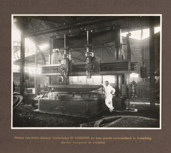 Bottom of first body Evaporation Sf. Gending ... In the foreground the tube plate, album page, photograph, Album page with a photo of a machine. Manufactured by Machinefabriek Braat for the Gending Sugar Factory. Part of the photo album Machinefabriek Braat Soerabaia-Djocja-Tegal, ca. 1916-1924., Surabaya, 1916 - 1924, photographer, Java, East Java, paper, pasteboard, gelatin silver print, developed gelatin silver print, height 154 mm x width 202 mm, height 240 mm x width 290 mm, Person, NV Machinefabriek Braat, Gending Sugar Factory, colonial system, machines, parts of machines, tools and appliances, factory-interior, machine shop (men (labourers)), economic history, overseas history, sugar industry, company history, Period, A large industrial machine occupies the center of the image, with a heavy circular platform at its base and a wide horizontal beam supported by vertical columns and mechanical housings with handwheels and gears; a man in a light-colored work uniform leans against ...