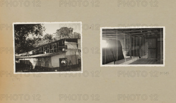 Industrial building, album page, photograph, Album page with two photos of the exterior under construction and the interior of an industrial building. Part of a photo album with photos of machines and structures of the NV Machinefabriek Braat in Surabaya, Sukabumi, and Tegal from the period 1931-1937., Java, 1931 - 1937, photographer, paper, pasteboard, gelatin silver print, height 87 mm x width 118 mm, height 250 mm x width 320 mm, Person, NV Machinefabriek Braat, factory-building, making the overground structures (, building activities), factory-interior, machine shop, economic history, overseas history, business history, Period, A sheet of aged paper with two black-and-white photographic prints affixed, the left print showing an exterior view of a multi-level wooden building with corrugated metal siding and a sloped roof, surrounded by trees and foliage with shadows cast across the structure, visible windows, doorways, and a small ladder leaning against the lower section, and the ri...