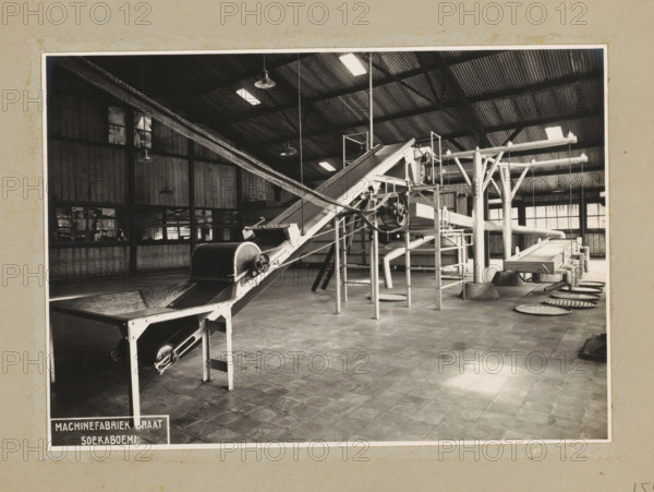 Installation, album page, photograph, Album page with a photo of an installation with conveyor belts. Designed for or by NV Technisch Bureau Van Assendelft De Coningh. Part of a photo album with photos of machines and constructions of the NV Machinefabriek Braat in Surabaya, Sukabumi, and Tegal from the period 1931-1937., 1931 - 1937, photographer, Java, West-Java, paper, pasteboard, gelatin silver print, developing gelatin silver print, height 161 mm x width 228 mm, height 250 mm x width 320 mm, Person, NV Machinefabriek Braat, factory-interior, machine shop, machines, parts of machines, tools and appliances, economic history, overseas history, company history, Period, An interior view of a large industrial room with a tiled floor and a corrugated metal roof supported by exposed beams, containing a network of metal machinery and conveyor belts with pulleys and rollers, angled chutes and vertical supports, hanging industrial lights from the ceiling, tall paneled walls with windows alon...