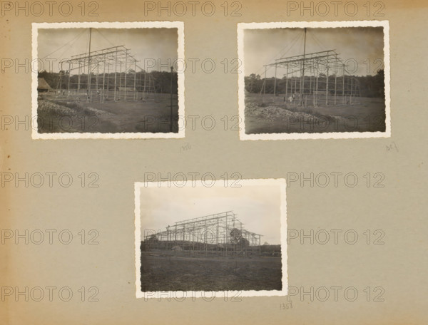 Skeleton construction, album page, photograph, Loose album page with three photos of the steel skeleton construction for an industrial hall. Part of a photo album with photos of machines and structures of the NV Machinefabriek Braat in Surabaya, Sukabumi, and Tegal from the period 1931-1937., Java, 1931 - 1937, photographer, paper, pasteboard, gelatin silver print, developed gelatin silver print, height 85 mm x width 110 mm, height 250 mm x width 320 mm, Person, NV Machinefabriek Braat, making the carcass (, building activities), economic history, overseas history, company history, Period, A beige album page shows three attached sepia photographs with scalloped white borders, arranged with two near the top and one centered below; each photo depicts a skeletal metal framework of a large structure on a flat dirt area with piles of rocks in the foreground and trees along the horizon, thin cables angling down from a tall central mast, and small groups of people and scattered equipment near...