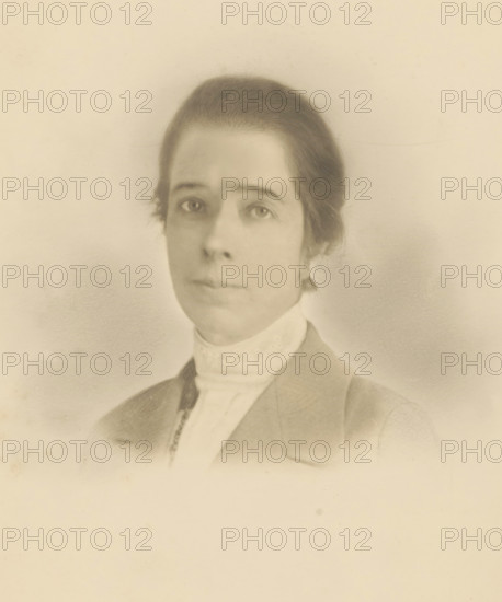 Portrait of unknown woman, photograph, photographer: circle of Cornelia Hendrika Jonker, 1880 - 1920, paper, pasteboard, gelatin silver print, developing gelatin silver print, height 240 mm x width 178 mm, height 235 mm x width 174 mm, historical persons - BB - woman, A faded sepia portrait of a person shown from the shoulders up, with hair pulled back and a high lacy collar visible beneath a jacket, soft shading around the face, neutral expression, and a plain light background.