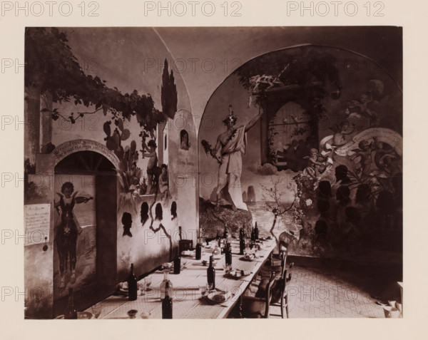 Hotel Pagano, Interior of the dining room of Hotel Pagano on Capri, Italy, Capri, photograph, number: '6174', inscription: 'Capri', photographer: attributed to Giorgio Sommer, Isola di, 1857 - 1914, Attributed to, pasteboard, paper, albumen print, height 317 mm x width 445 mm, hotel, hostelry, inn, A long dining table set with plates, glasses, napkins, and upright bottles runs through the foreground toward the back of the room, surrounded by wooden chairs, while the walls are covered with large painted murals depicting figures, animals, foliage, arches, and decorative scenes; silhouettes of heads appear painted on one wall near a small arched niche with painted figures, and a life-sized painted person appears on the left wall near a painted archway; a central painted figure draped in cloth stands beneath an arched mural opening, a festive cluster of cherubic figures and playful creatures occupies the right mural area, and a painted landscape with cliffs and water is visible in the back...