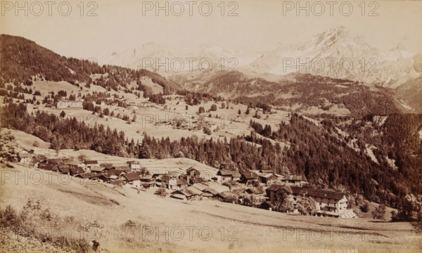 Chesieres Villars, View of Villars-sur-Ollon in Switzerland, photograph, number: '1781', collector's mark: 'VOSMAER', Villars-sur-Ollon, 1900, photographer, paper, albumen print, albumendruk, height 132 mm x width 221 mm, city view in general, 'veduta', mountains, A wide sepia-toned landscape showing a mountain valley with clustered buildings and houses in the foreground along a sloping grassy hillside, a band of dense conifer forest rising behind them, scattered individual trees and small clearings across rolling meadows in the middle ground, larger multi-story buildings on a distant slope, and rugged snow-dusted mountain peaks and ridgelines forming the background under a pale sky.