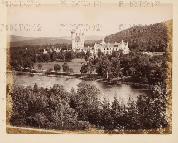 Balmoral, from the river, Balmoral Castle, album page, photograph, This page is part of an album., number: '315, JV', Aberdeenshire, c. 1875 - c. 1885, photographer, paper, albumen print, height 298 mm x width 236 mm, river, castle, A large pale stone building with multiple turrets and a taller central tower sits amid a landscaped lawn and clusters of trees, with a river flowing in the foreground and wooded hills rising behind the estate, all shown in a high-contrast monochrome photograph.