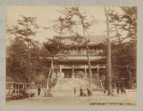 Gate of Chion-in Temple, Kyoto, 37. Gate of Chionin Buddhist Temple. - Kyoto, photograph, number: '6.', c. 1895 - c. 1915, photographer, Kinki, paper, pasteboard, albumen print, height 207 mm x width 273 mm, height 243 mm x width 329 mm, A wide sepia photograph shows a large traditional wooden gate with a tiled roof partially obscured by tall trees with thin trunks and spreading branches; wide stone steps lead up to the gate and a few people in traditional clothing stand or walk near the base of the steps, with some gathered around a carrying pole and baskets; to the left are simple wooden benches and a pergola-like wooden structure, while the foreground is an open dirt area with scattered small objects and tree stumps.
