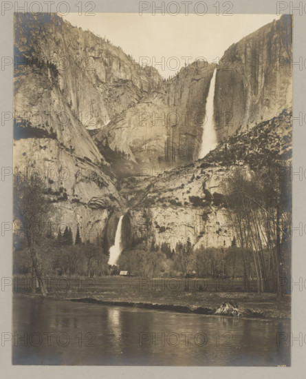 Yosemite waterfall, photograph, Bottom right reads: 10109., annotation: '2. Yosemete-fall.', California, c. 1895 - c. 1915, photographer, North America, paper, pasteboard, gelatin silver print, developing gelatin silver print, height 238 mm x width 189 mm, height 329 mm x width 243 mm, A sepia-toned landscape photograph showing a tall, steep rock face with two prominent waterfalls cascading down different sections of the cliff; the upper waterfall falls from near the top of the rock into a misty basin below while the lower waterfall continues down to a tree-lined valley; rocky slopes and scattered trees cover the cliff surfaces, with clusters of trees at the base and leafless trees along the right foreground; a reflective river runs across the bottom of the image with rippled reflections and a small grassy bank; a small building with a pitched roof sits near the treeline, partially obscured by trees.