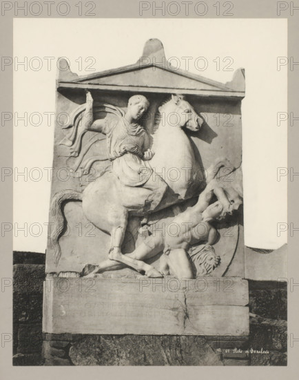 01 Stele of Dexileos, Stela of Dexileos, photograph, number: '32.', Athens, c. 1895 - c. 1915, photographer, Athene, Periféreia Protevoúsis, pasteboard, paper, collotype, photoprint, height 273 mm x width 215 mm, height 328 mm x width 239 mm, A rectangular stone relief framed by a triangular pediment shows a scene with a mounted figure and a fallen male figure; the mounted figure wears draped clothing and a cloak flowing behind, sits astride a rearing horse with a detailed mane and raised front leg, and holds a small object in one hand while the other arm is raised; the fallen male figure is muscular, reclined against the base with one arm raised to shield his head and his body twisted beneath the horse; carved decorative lines and contours define muscles, drapery, and the horse’s tail, and the relief sits on a stone plinth with a cracked surface and a darker textured base beneath.