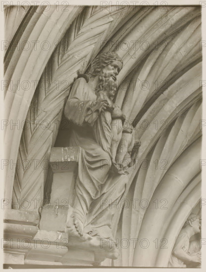 Fürstentor, Dasselbe, Abraham vl, Detail of the Fürstenportal in the cathedral of Bamberg, album page, photograph, This photo is part of an album., inscription: 'Kunsthist. Seminar, Marburg (Lahn), Photogr. Abteilung, Vervielfältigung, untersagt.', number: '109', Bamberg, 1900 - c. 1920, photographer, Bavaria, paper, baryta paper, gelatin silver print, developing gelatin silver print, height 238 mm x width 179 mm, church (exterior), Bamberg Cathedral, A stone sculpture of a robed, bearded man holding a smaller robed child is set within a series of carved, ribbed archways; the larger figure has wavy hair and a downward gaze, detailed drapery folds cascade over a ledge, and the child's legs and feet are visible as the adult's hands support the child; the surrounding arches display repeating curved and diagonal grooves and weathered surface texture, and a partial second figure appears in a recessed arch on the right.