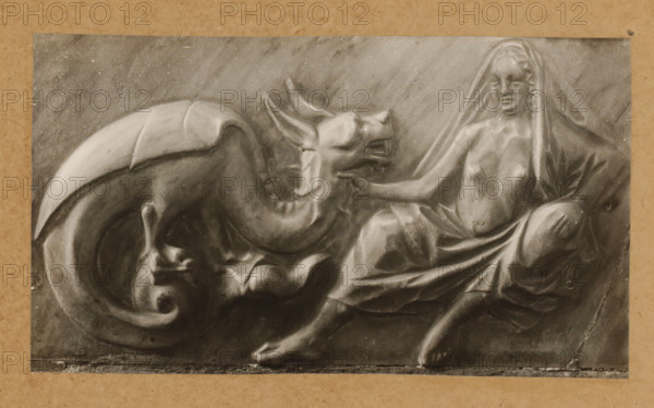 Detail of the tomb of Pope Clement II in the cathedral of Bamberg, Grabmal, Keuschheit, album page, photograph, This photo is part of an album., number: '139', Bamberg, 1900 - c. 1920, photographer, Bavaria, paper, baryta paper, gelatin silver print, developing gelatin silver print, height 127 mm x width 225 mm, Person, Clemens II, interior of church, Bamberg Cathedral, A carved relief showing a reclining draped female figure with a partially covered head and torso reaching toward a large reclining dragon-like creature with a curled tail and open mouth, all rendered in a smooth stone texture against a flat background and framed by a plain border.