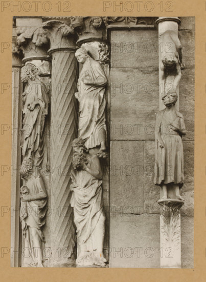 Detail of the Princely Portal in Bamberg Cathedral, Princely Gate Statues of the 5th and 6th century of Judas Column, album page, photograph, This photo is part of an album., number: '93', Bamberg, 1900 - c. 1920, photographer, Bavaria, paper, baryta paper, gelatin silver print, height 221 mm x width 160 mm, church (exterior), Bamberg Cathedral, A vertical stone relief showing carved figures and decorative columns set into a wall panel, with several robed human figures in various poses and expressions carved in a weathered stone texture, a twisted fluted column between groups of figures, ornate capitals with acanthus-like carvings, a figure suspended upside down attached to a narrow column, and a standing figure on a carved plinth, all rendered in a monochrome stone tone against a plain masonry background.