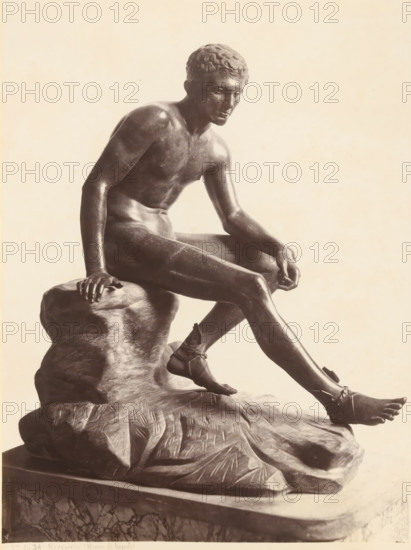 Bronze sculpture of Mercury, Museo di Napoli Mercurio, album page, photograph, This photo is part of an album., number: '1834', workshop stamp: 'Giorgio Sommer, Largo Vittoria, Napoli', photographer: Giorgio Sommer, Naples, 1874 - in or before 1879, paper, albumen print, height 248 mm x width 186 mm, (story of) Mercury (Hermes), sculpture (bronze, arts), A monochrome photograph of a seated male statue shown from the head to the lower legs, depicting a bare-chested figure with short curly hair and a contemplative facial expression, one arm resting on a rocky base and the other arm relaxed with the hand near the knee, muscular torso and limbs rendered with smooth surfaces and subtle highlights, the figure wearing simple sandals with straps around the ankles, the statue positioned on a textured rock-like support atop a rectangular plinth, and a plain, light background surrounding the sculpture.