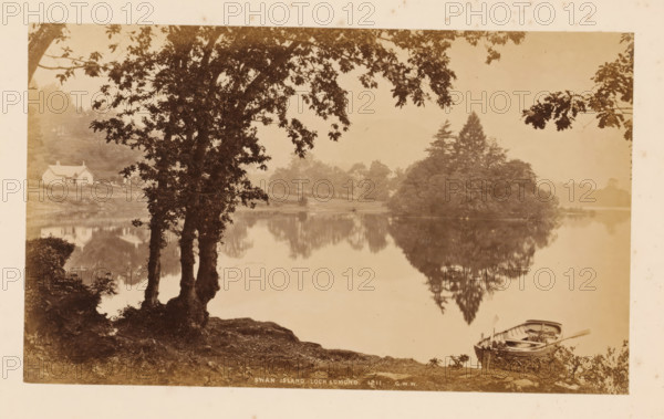 View of Swan Island in Loch Lomond, Swan Island, Loch Lomond, photograph, number: '1211, GWW', photographer: George Washington Wilson, Scotland, 1865 - 1880, paper, albumen print, height 116 mm x width 192 mm, island, landscapes with waters, waterscapes, seascapes (in the temperate zone), A sepia-toned lakeside scene with a calm body of water reflecting trees and shoreline. In the foreground left, a large tree with multiple trunks and overhanging branches frames the view, its roots and surrounding ground visible. Near the right foreground, a small wooden rowboat rests at the water’s edge with oars and interior details visible. Across the lake, a densely treed island rises with a mix of rounded foliage and taller coniferous shapes, its reflection mirrored in the water. On the far left shore, a light-colored cottage with a pitched roof sits among grassy banks and scattered trees. The sky appears pale and hazy above the distant tree line.