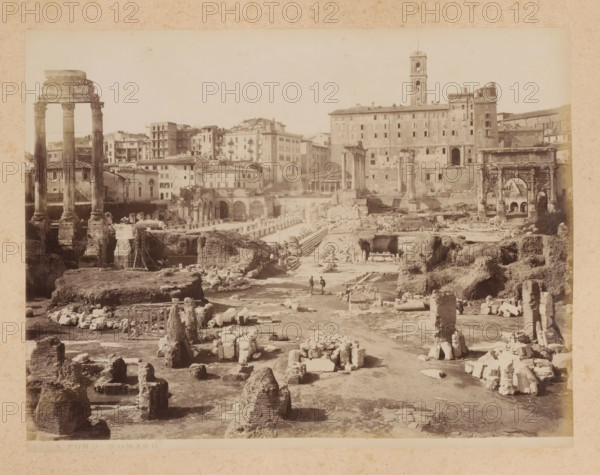 View of the Roman Forum in Rome, album page, photograph, This photo is part of an album., inscription: '292 FORO ROMANO', Rome, 1870 - c. 1895, photographer, paper, pasteboard, albumen print, height 198 mm x width 257 mm, ruin of a building, architecture, Roman Forum, A wide sepia photograph of an archaeological site showing scattered stone ruins and fragmented columns across uneven ground, with three tall standing columns with carved capitals on the left and a large archway structure with decorative details on the right, a long multi-story building with many windows and a tower rising behind the central area, rows of arches and stone stairways amid the ruins, rubble piles and stone blocks arranged in the foreground, and two small human figures walking along a pathway near the center of the scene.