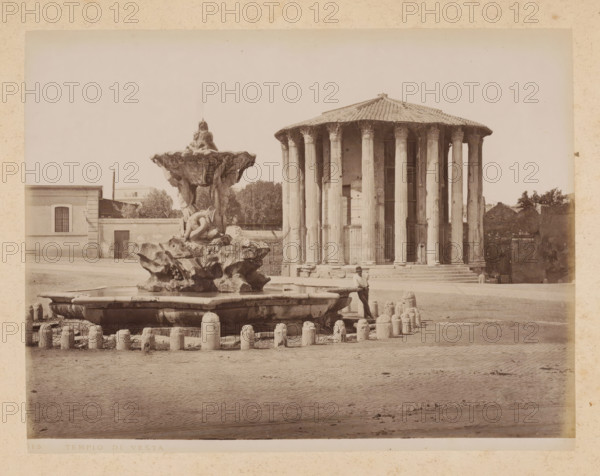 View of the Temple of Hercules Invictus in Rome, album page, photograph, This photo is part of an album., inscription: '515 TEMPIO DI VESTA', Rome, 1870 - c. 1895, photographer, paper, pasteboard, albumen print, height 199 mm x width 258 mm, temple, shrine, Roman religion, (story of) Vesta (Hestia), Temple of Hercules Invictus, A wide sepia photograph showing a circular ancient temple with a tiled conical roof supported by tall fluted columns standing on a stepped base, positioned toward the right side of the image, and a large ornate fountain with a sculpted rocky base and carved figures rising from its center in the left foreground; a man in a hat leaning against the fountain edge is visible, stone bollards encircle the fountain, a low building with a barred window sits behind the fountain at left, trees and a low wall are behind the temple, and the scene rests on a broad paved open area under a pale sky.