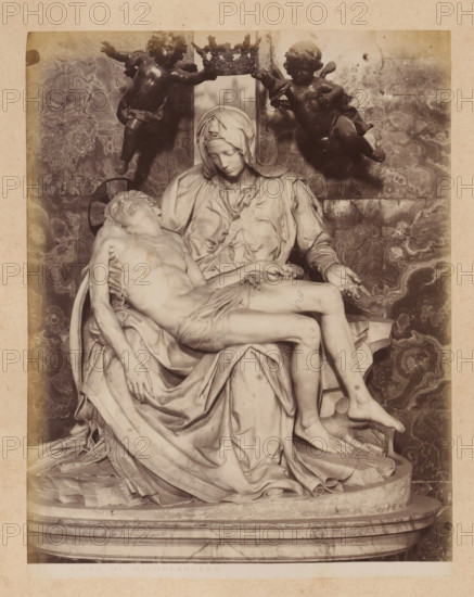 Pietà by Michelangelo in St. Peter's Basilica in Vatican City, album page, photograph, This photo is part of an album., inscription: '181 PIETA DI MICHELANGELO', St. Peter's Basilica, 1870 - c. 1895, photographer, Vatican City, paper, pasteboard, albumen print, height 259 mm x width 200 mm, piece of sculpture, reproduction of a piece of sculpture, interior of church, the dead Christ in Mary's lap, A monochrome photograph of a marble sculpture showing a seated woman wearing a head covering and flowing drapery, holding the limp body of a man across her lap; the woman's head is bowed and her hands support the man's torso and legs, while two winged childlike figures hover above holding a decorative crown between them; the figures rest on a rounded base with draped cloth and carved folds, and a patterned stone wall serves as the backdrop.