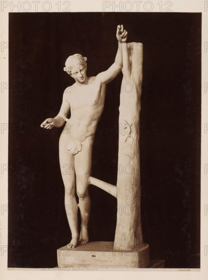 Sculpture of Apollo Sauroctonus, Vatican, Apollo Sauroctonus, album page, photograph, This photo is part of an album., inscription: '1309 M. Vat. APOLLO SAUROCTONOS Anderson', photographer: James Anderson, Vatican Museums, after sculpture by anonymous, c. 1857 - c. 1875, after sculpture by, Vatican City, paper, albumen print, height 376 mm x width 280 mm, piece of sculpture, reproduction of a piece of sculpture, A pale statue of a nude male figure stands next to a tall, textured vertical post with a horizontal support, the figure leaning with one arm raised and grasping the post while the other arm extends outward with an open hand; the figure has curly hair styled close to the head, a serene facial expression with downcast eyes, and a naturalistic, well-defined torso and limbs; the statue is mounted on a rectangular base and photographed against a dark background, with the post showing carved vine-like details and the surface of the sculpture displaying smooth and slightly weathered t...