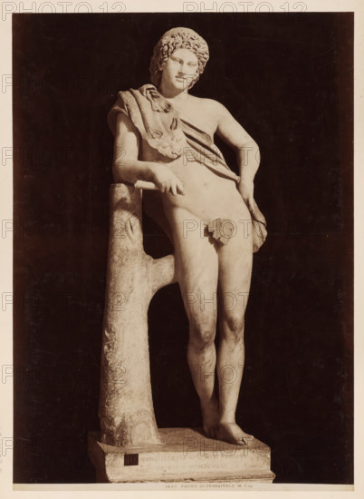 Sculpture of a faun, after Praxitiles, in the Capitoline Museums in Rome, 1683. Fauno di Prassitele M. Cap, album page, photograph, This photo is part of an album., inscription: '1683. Fauno di Prassitele M. Cap.', photographer: attributed to James Anderson, Capitoline Museums, after sculpture by anonymous, c. 1857 - c. 1875, after sculpture by, Rome, Attributed to, paper, albumen print, height 384 mm x width 275 mm, piece of sculpture, reproduction of a piece of sculpture, satyr(s) (in general), A photograph of a marble statue of a nude youth leaning against a rough, tree-like support, the figure shown from head to feet with curly hair and a relaxed facial expression, a draped cloth across one shoulder and torso with a lionhead detail on the cloth, an ornamental leaf placed over the groin, one arm resting on the support and the other hand touching the hip, the legs gently crossed at the ankles and the feet positioned on a rectangular plinth, the statue set against a dark background an...