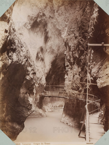 Bridge in the Trient Gorge, Vernayaz. Gorges du Trient, album page, photograph, This photo is part of an album., inscription: '13939 Vernayaz. Gorges du Trient. Sommer - Napoli', photographer: Giorgio Sommer, Trient (Switzerland), 1880 - 1890, paper, albumen print, height 255 mm x width 196 mm, ravine, chasm, abyss, canyon, Tall steep rock faces form a narrow gorge with smooth and jagged textures in shades of brown and grey, a pale river flowing at the base, and a series of wooden walkways and railings attached to the rock, winding along the cliff edge and crossing between rock walls.