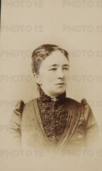 Portrait of a woman from the Marmelstein family, presumably the mother-in-law of AF Marmelstein, photograph, carte-de-visite, inscription: 'Photographie, Parisienne, H. van der Zijl, Nieuwendijk 60, over Raamskooi, Amsterdam., Please note the correct address.', photographer: H. van der Zijl, Amsterdam, 1886 - 1900, paper, pasteboard, albumen print, albumendruk, height 103 mm x width 64 mm, historical persons not known by name - BB - woman, A sepia-toned portrait of a woman from the chest up, facing slightly to her right with a neutral expression, wearing a high-collared dark dress with a textured lace front and a small decorative clasp at the throat, her hair styled back and parted on the side, visible shoulders with puffed sleeves, and a plain light background.